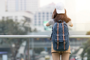 Back view of young Asian woman tourist looking at the sights of city. Travel and vacation concept.