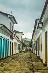 Centro histórico de Paraty/RJ com casarões coloniais e ruas de pedra em dia nublado, destacando a arquitetura histórica e o charme das ruas típicas da cidade.