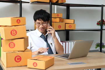 Young Asian entrepreneur owner talking on phone at workplace at home. Start up small business.