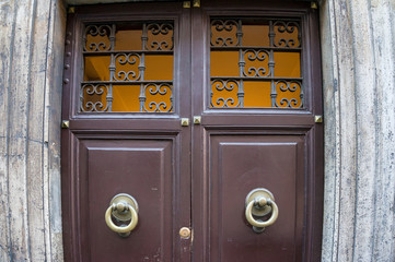 Close up of closed wood door with door knobs, handles and cast iron latice work
