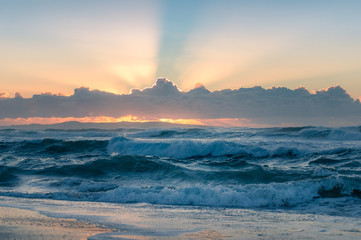 Ocean seascape with heavy waves and spectacular sun rays or god rays