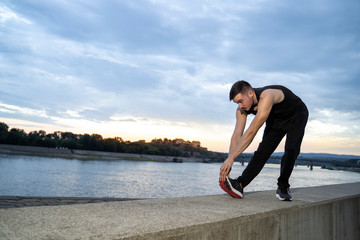 Fototapeta na wymiar Young man stretching legs before run outdoors 