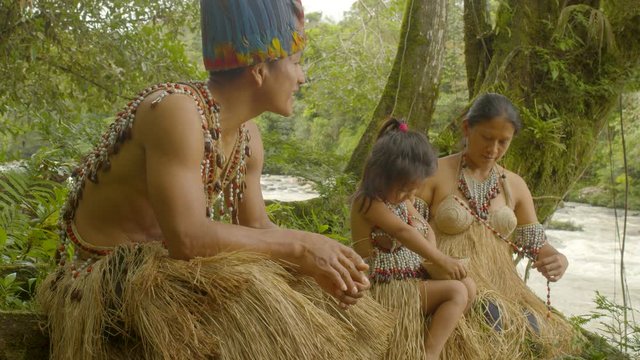 Indigenous Family Making Necklaces At The Edge Of A River In Ecuador