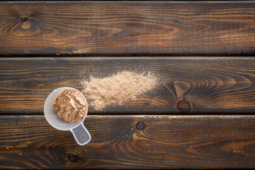 Sports nutrition with scoop and protein on wooden background top view