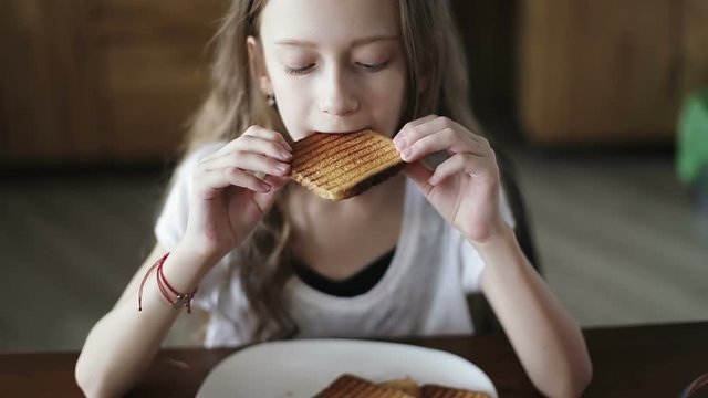 Portrait of a beautiful schoolgirl eating white bread toast.