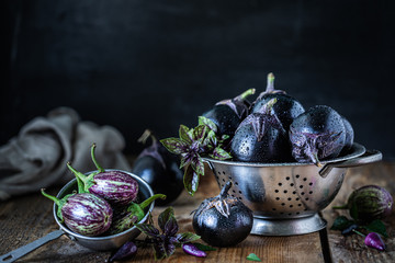 Eggplants of different colors and different grades on a wooden table.