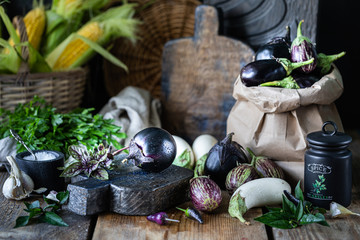 Eggplants of different colors and different grades on a wooden table.