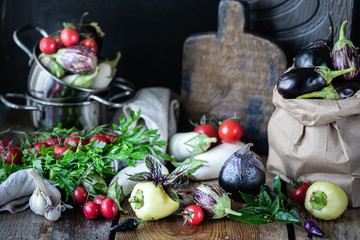 Eggplants of different colors and different grades on a wooden table.