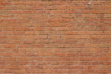 Old reddish orange brick wall background with cracks and worn texture