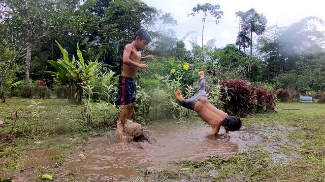 Indigenous Children Playing In A Puddle Of Water In Ecuador