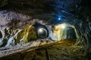 Dark dirty abandoned uranium mine with rusty remnants of railway