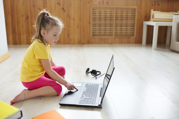 Cute girl online at the laptop. The child sits on the Internet.