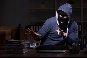 Male thief in balaclava in the office night time