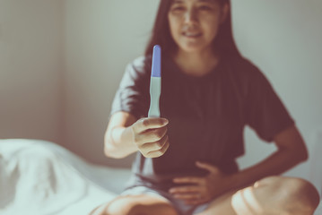 Obraz na płótnie Canvas Happy asian woman hands holding pregnancy test after testing in her bedroom