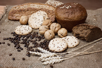 Many kinds of whole wheat bread, sesame cookies, walnuts and coffee beans and wheat spikelets are laid out on a coarse burlap. The concept of a healthy Breakfast. Image still life and selective focus.