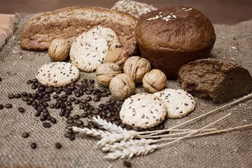 Fotobehang Many kinds of whole wheat bread, sesame cookies, walnuts and coffee beans and wheat spikelets are laid out on a coarse burlap. The concept of a healthy Breakfast. Image still life and selective focus. © Елена Труфанова