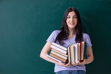 Young female teacher student in front of green board