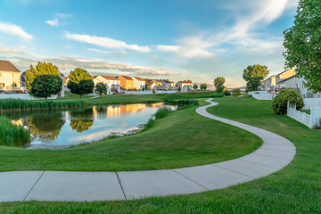 Homes overlooking a grassy park with shiny pond and winding pathway - Powered by Adobe