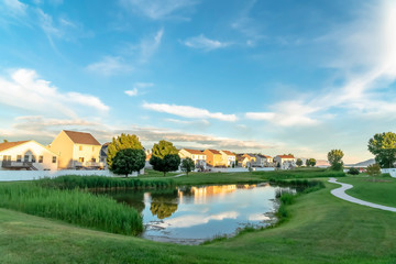 Obraz premium Shiny pond reflecting cloudy blue sky on a scenic neighborhood on a sunny day