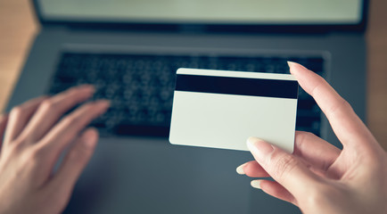 Hand holding credit card and press laptop computer enter the payment code for the product. Pay online for convenience.