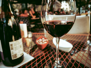 wine glass full with red wine in front of bokeh cafe scene