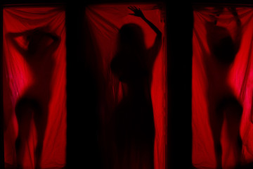 Woman behind red curtains