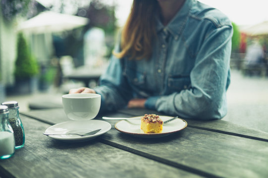Young woman drinking coffee and eating cake