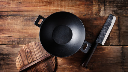 Empty cast iron wok and and knife, top view. Copy spase. Oriental style. - obrazy, fototapety, plakaty