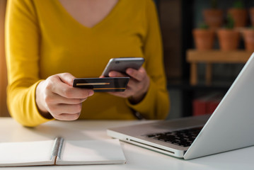 Female businessman use credit cards to conduct financial transactions through phones, tablet, and laptop.