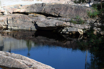 Fototapeta na wymiar Calm river between rocks. Deer shape shadow on rock.