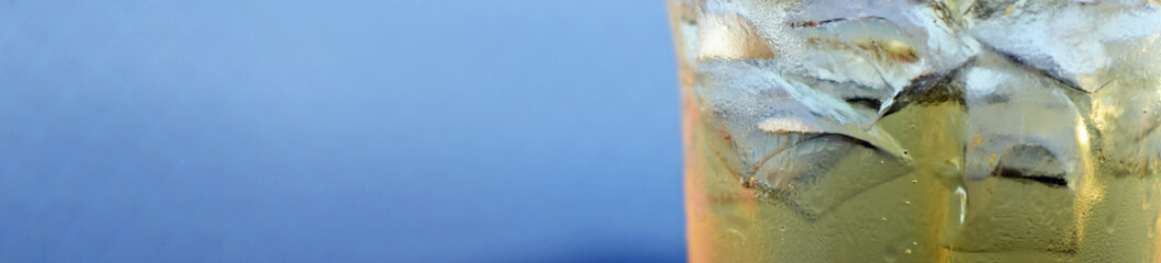 Close up of cider with ice cubes. Cold summer drink for refreshment. Panoramic banner background with copy space.