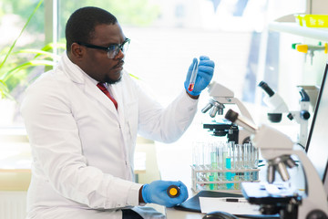 African-american medical doctor working in research lab. Science assistant making pharmaceutical...