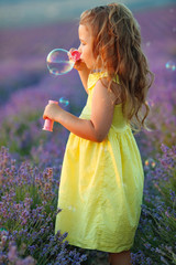 A child with soap bubbles. Little girl in a field with flowers.
