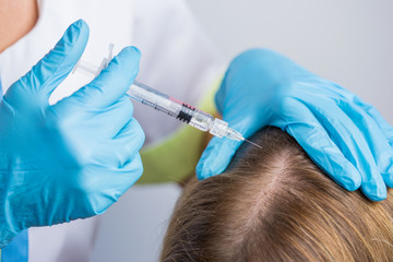 The doctor cosmetologist making mesotherapy injections in woman's head for stronger and healthier hair.