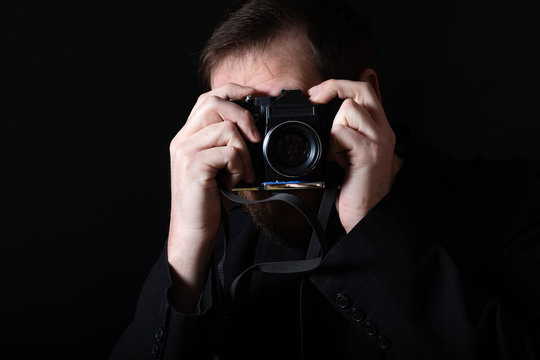 man with an old film camera on a dark background