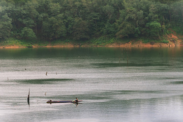 Fisherman and small fishing boat and floating in Bang Lang reservoir in the rain.