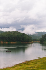Fototapeta na wymiar Fisherman and small fishing boat and floating in Bang Lang reservoir in the rain.