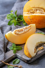 Slices of ripe yellow melon on a wooden board.
