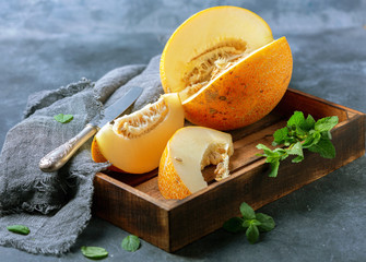 Slices of ripe yellow melon in a wooden tray.