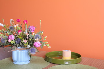 Vase with a bouquet of flowers on a orange wall background