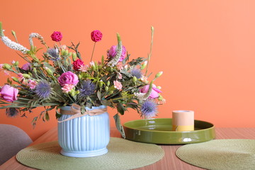 Vase with a bouquet of flowers on a orange wall background