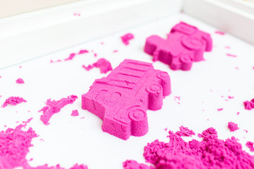 Truck and train made with a pink kinetic sand on a white background.