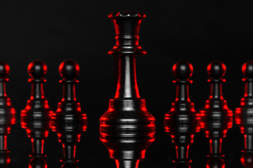 Chess pieces on dark background with red backlight close up