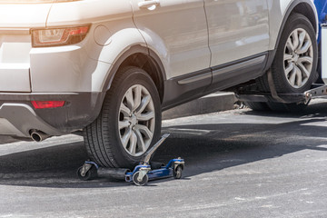 Hooked up car on a tow truck on a roadside, close up view of the rear wheel of a car and a...