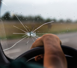 Broken windshield of a car. A web of radial splits, cracks on the triplex windshield. Broken car...