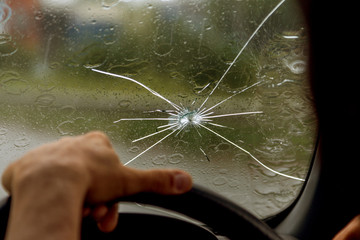 Broken windshield of a car. A web of radial splits, cracks on the triplex windshield. Broken car...