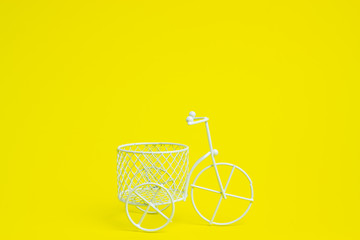 Fototapeta na wymiar A toy bike. The idea for a postcard. Yellow background. Minimalism.