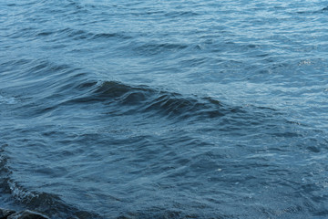 Blue water with waves and sun reflections background