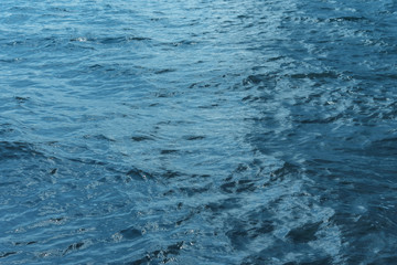 Obraz premium Blue water with waves and sun reflections background