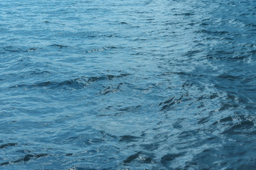 Blue water with waves and sun reflections background